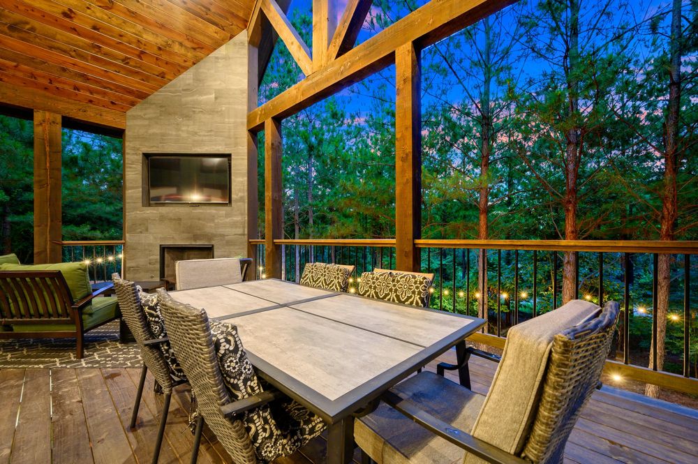 The covered back deck at dusk, table set under the pines